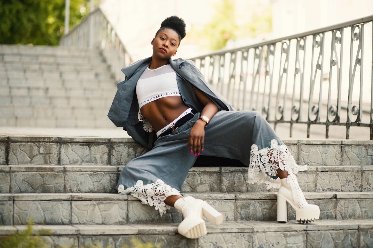 Customer on outdoor steps wearing a grey suit with lace-trim trousers and white platform boots